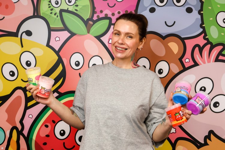 Ruby Sheldon, founder of Putty Pals, holding containers of Putty Pals.