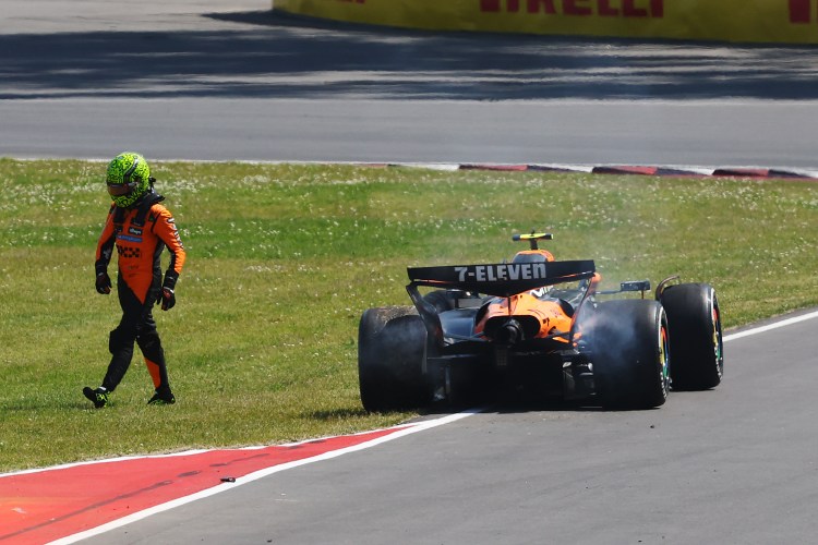 Lando Norris walking away from his damaged McLaren Formula 1 car after a crash.