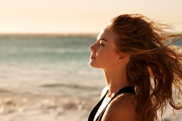 Woman standing on beach with windblown hair.