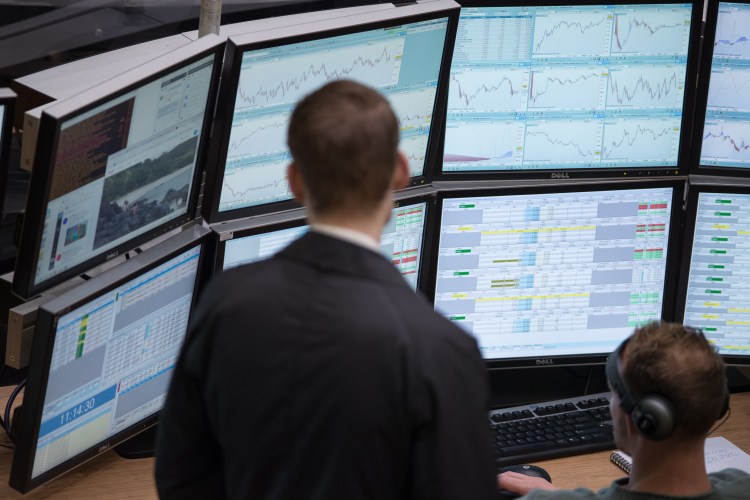 Traders at the Amsterdam Stock Exchange monitor stock market data on multiple computer screens.