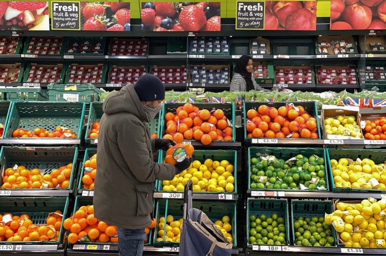 A shopper selects oranges in a Tesco supermarket.