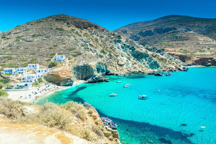 Agali Beach in Folegandros, Greece, with crystal-clear turquoise water and whitewashed buildings.