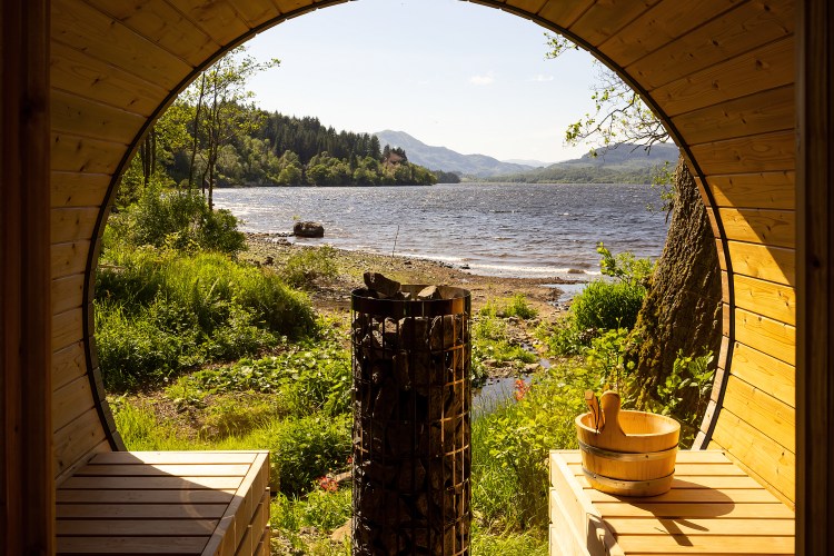 Wooden sauna with a view of a lake and mountains.