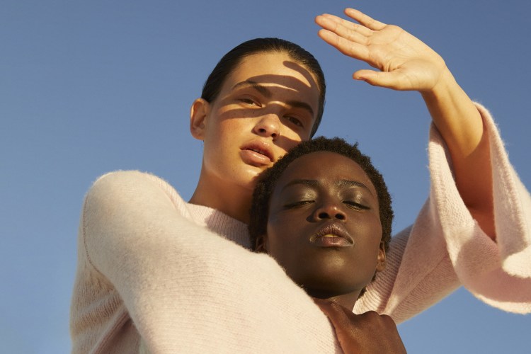 Two women embracing under a clear blue sky.