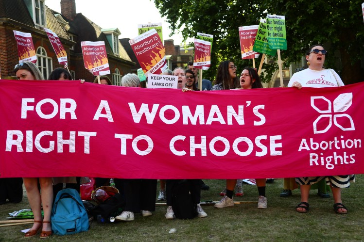 Pro-choice protestors holding a banner that reads "For a Woman's Right to Choose".