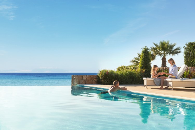Family relaxing by an infinity pool overlooking the ocean.