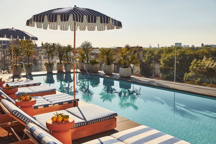 Rooftop pool with striped lounge chairs and city view.