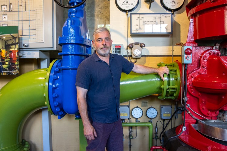 Richard Albanese, Project Manager of the London Museum of Water & Steam, standing near water pumps.