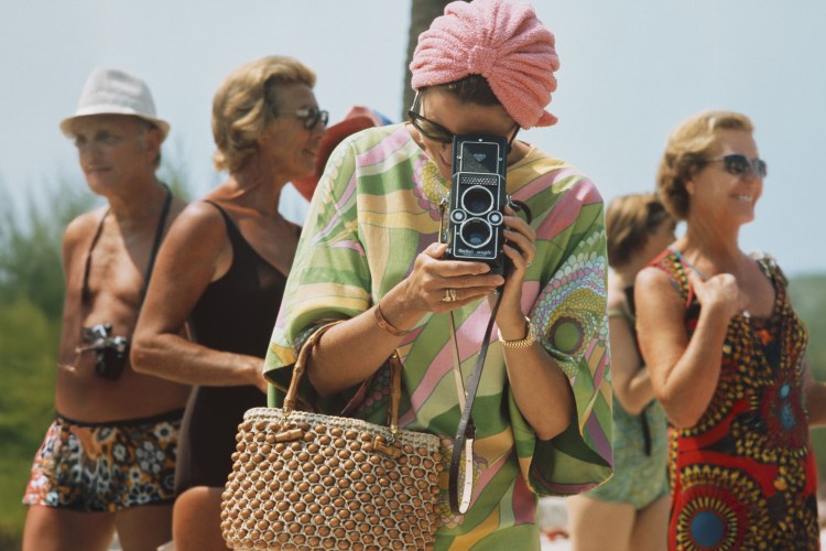 Princess Grace of Monaco taking a photograph with a Rollei Magic camera at a swimming competition.