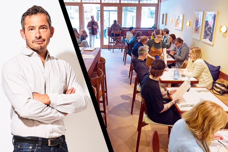 A man standing with his arms crossed next to a busy restaurant.