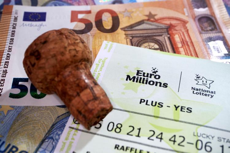 Winning EuroMillions lottery ticket with cash and champagne cork.
