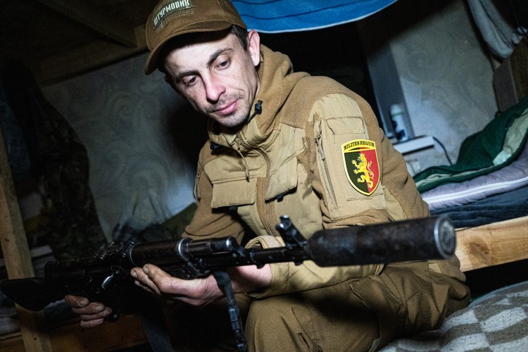 A soldier checks his machine gun.