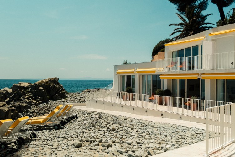 Beachfront house with yellow awnings and patio furniture.