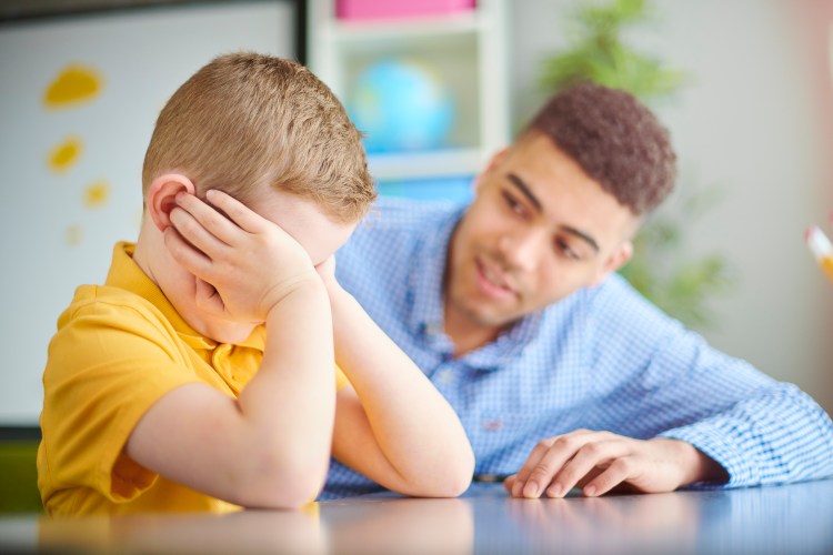 Upset schoolboy with his teacher.