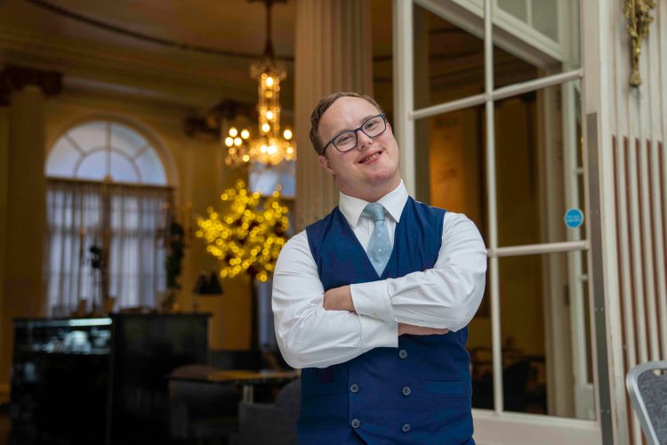 Portrait of Sam Innes, a Food and Beverage Assistant at The Waldorf Hilton, standing with his arms crossed.