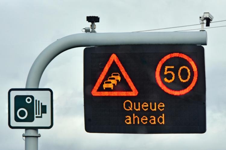 M25 motorway sign: 50 mph speed limit, queue ahead warning, CCTV cameras.