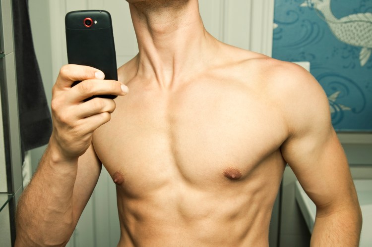 Shirtless young man taking a selfie in a mirror.