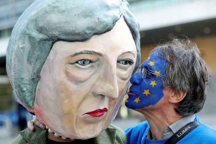 A demonstrator kisses a large puppet of Theresa May before a EU summit.