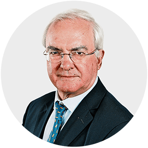 a man wearing glasses and a suit looks at the camera